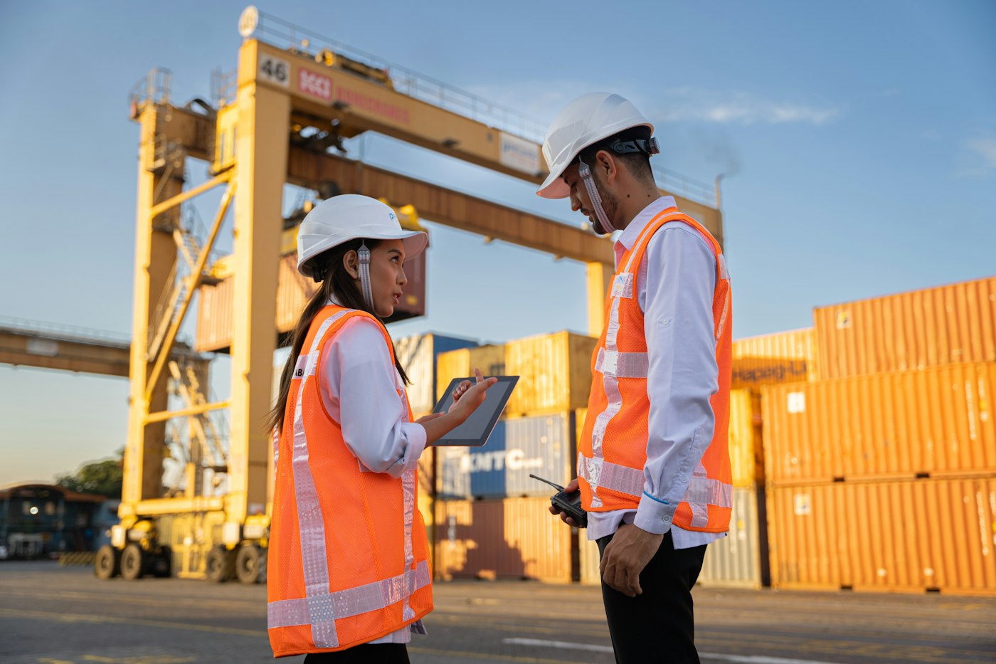 Two site personnel in hard hats reviewing plans on a logistics site