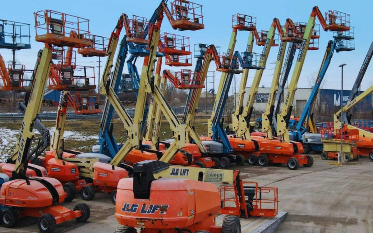 Boom lifts and aerial work platforms staged in a rental yard