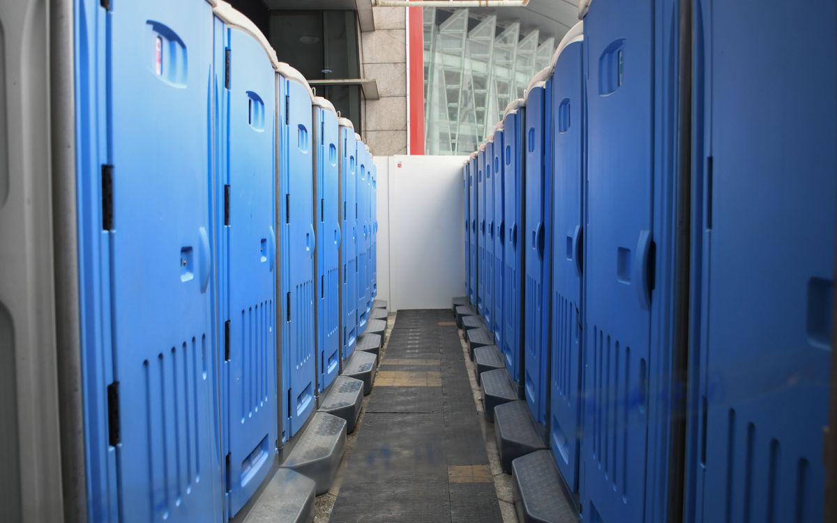 Portable restroom units staged in rows at an outdoor site